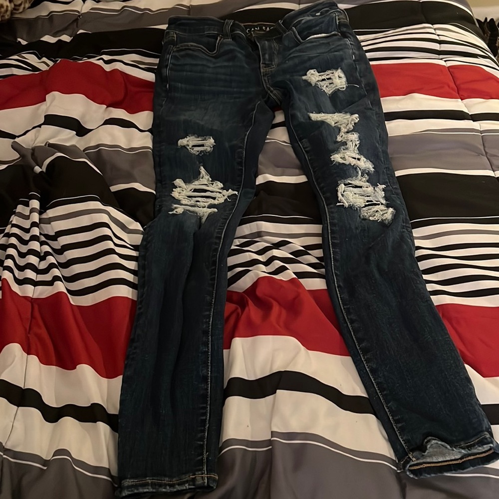 american egale dark navy blue jeans with patched holes .